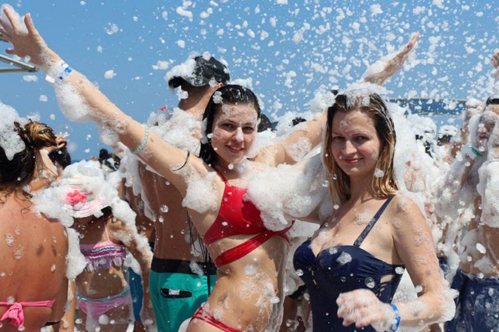Tourists dancing in foam during an afternoon party on the upper deck of a boat cruise from Manavgat near Side, Antalya