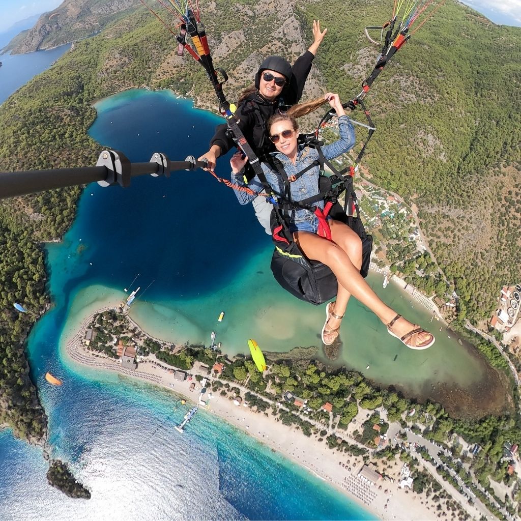 Female tandem paragliding pilot preparing equipment for passenger in Side