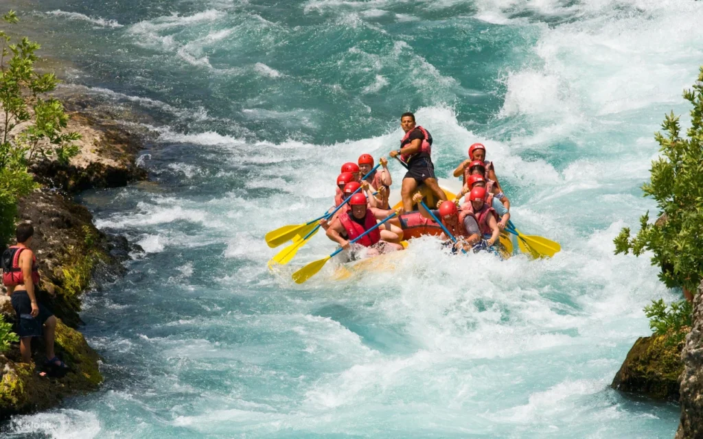 Family rafting on the Köprüçay River with safety helmets and life jackets during a Side day trip