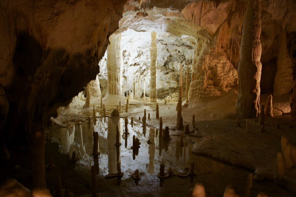 Illuminated stalactites and stalagmites along the wooden walkway inside Cüceler Cave near Sapadere Canyon