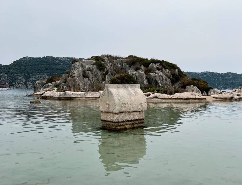 Ancient Lycian sarcophagus standing in the turquoise sea near Kaleköy and Simena Castle in Kekova, Turkey