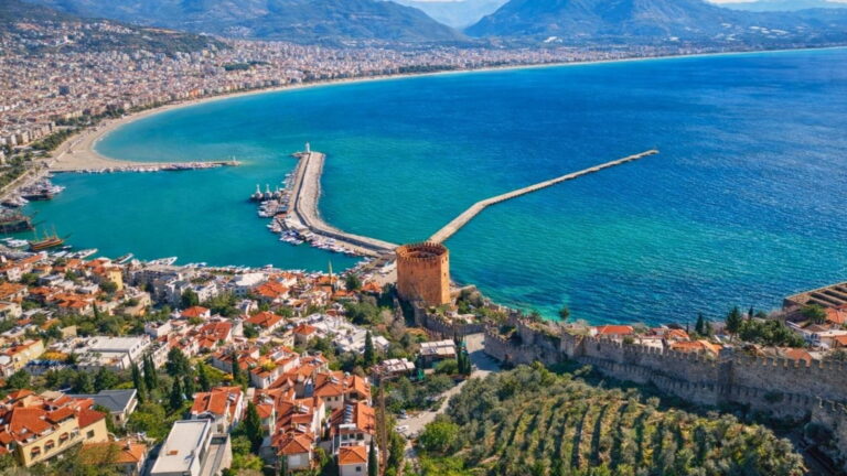 Historic stone fortifications of Alanya Castle overlooking turquoise sea and Cleopatra Beach on Side day excursion