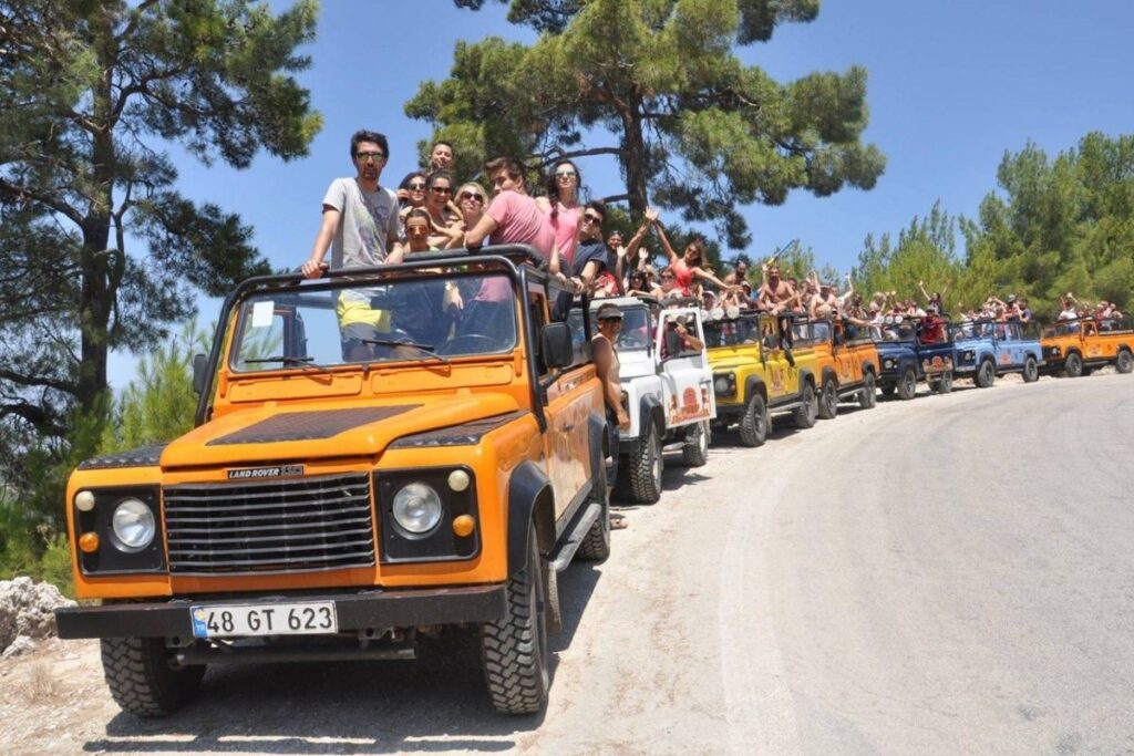 Tourists riding an open-top Jeep along a pine forest trail in Köprülü Canyon National Park near Side, Antalya, with the Taurus Mountains in the distance