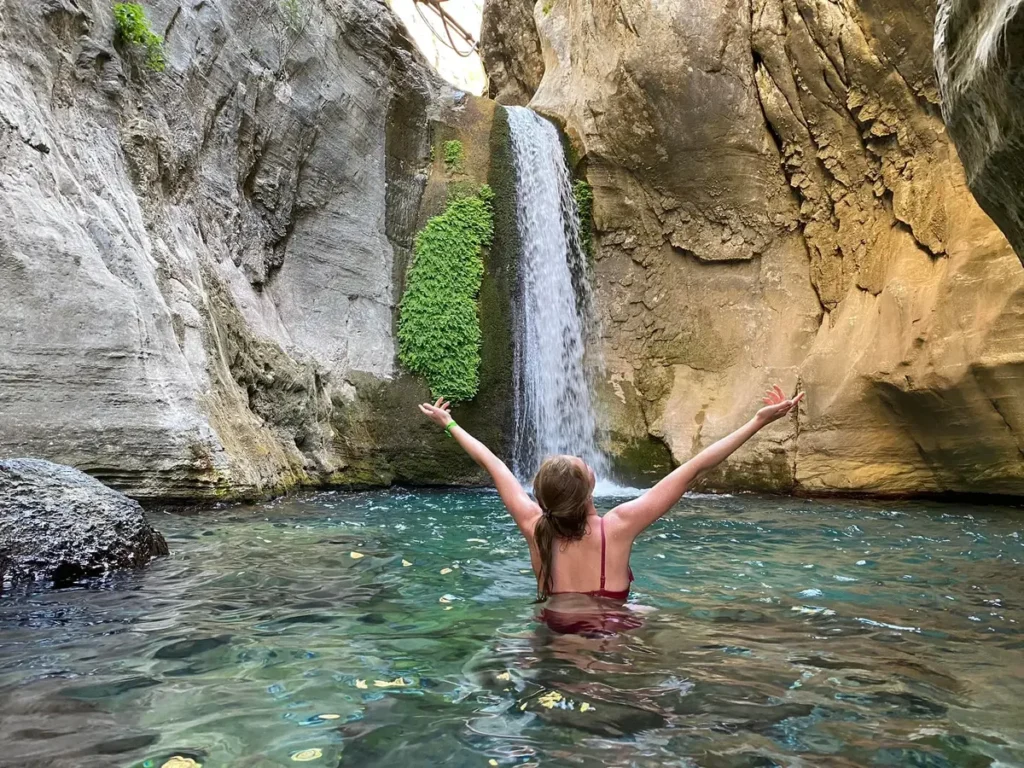 Tourist swimming in the clear mountain water beneath the main waterfall at Sapadere Canyon near Alanya