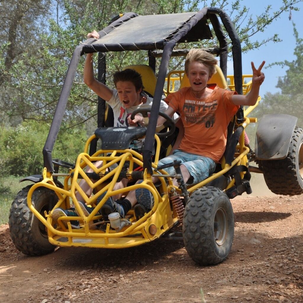 Teenager wearing a helmet and safely driving a buggy on a Side Manavgat off-road tour, no driver's license required.